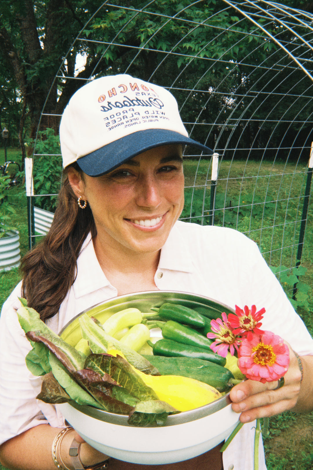 Macy W Johnston holding a bowl of fresh vegetables in an outdoor garden setting
