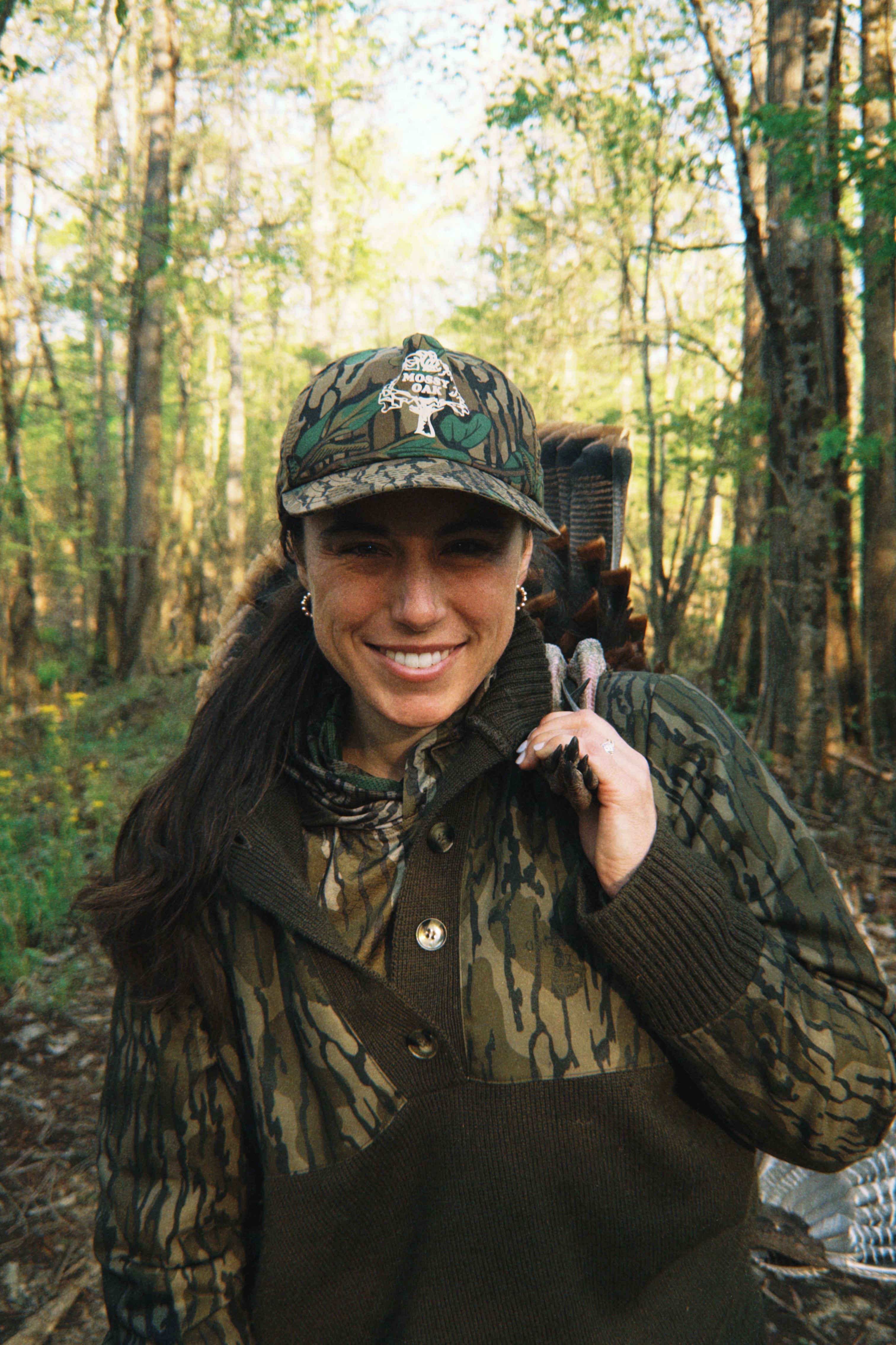 Woman in camouflage clothing and hat in a forest setting